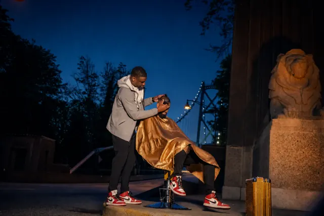 A barber concentrating on the shape and finish of a haircut